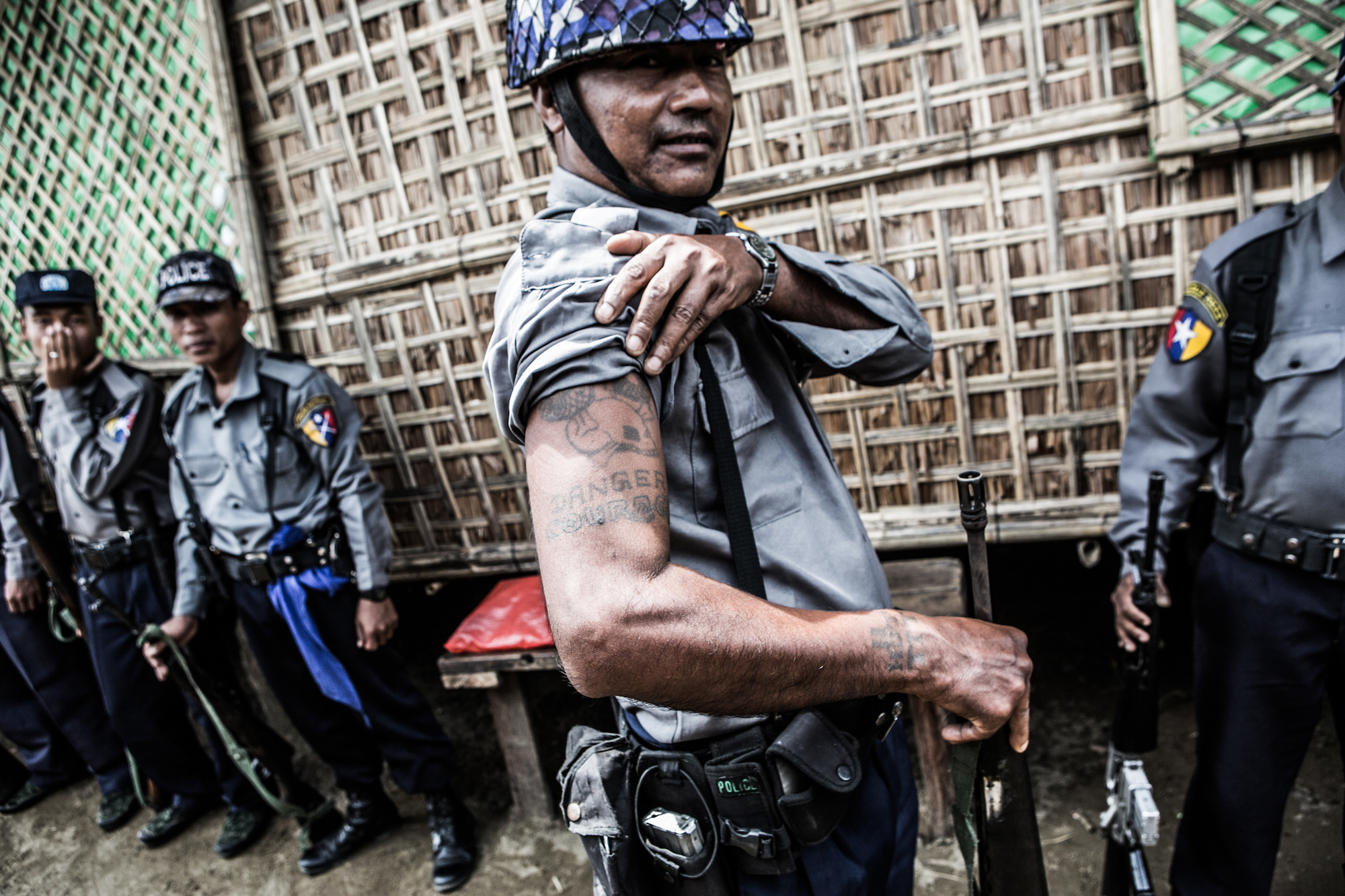 Een politie agent op  patrouille in één van de kampen toont zijn tattoages.