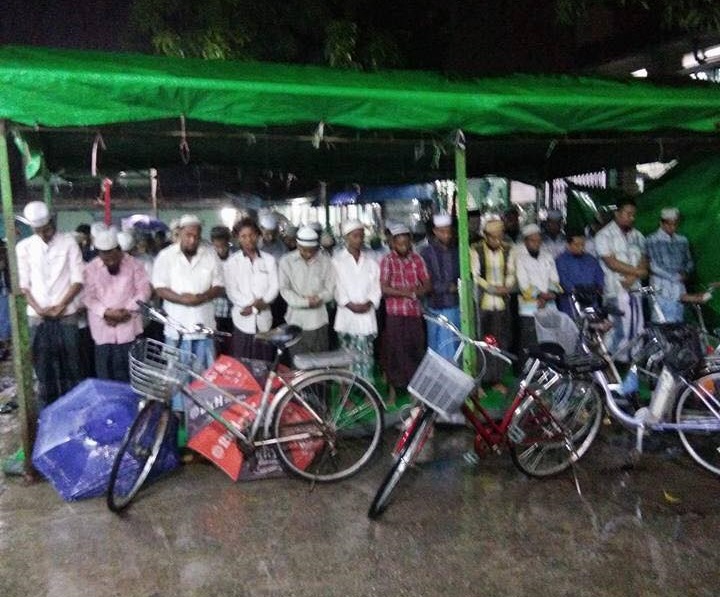 Onder plastic zeil kon een deel van de moslims relatief droog staan terwijl regen de straten van Yangon teisterde.